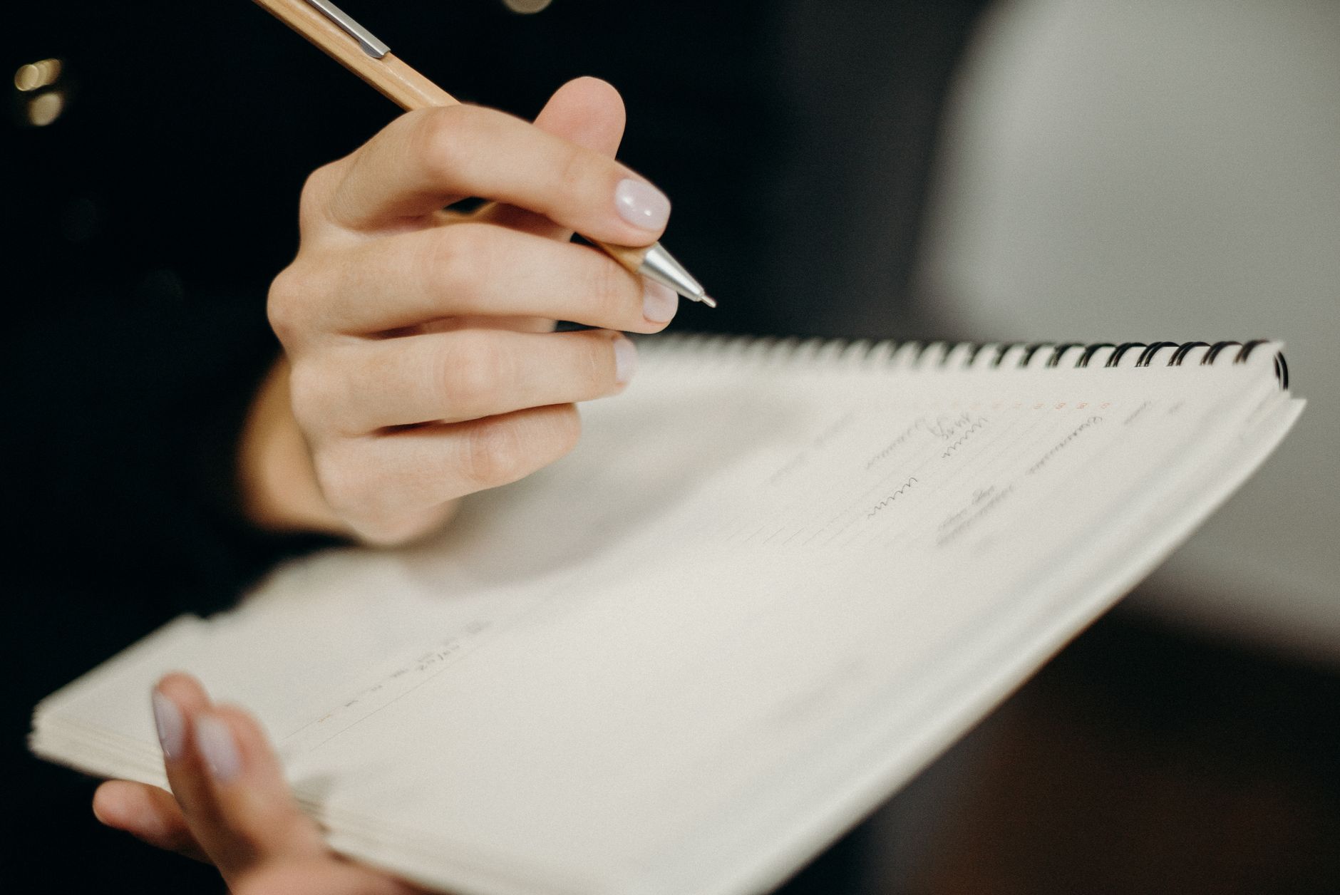 Person writing garden notes in a notebook while planning next season's crops